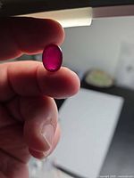 Oval ruby held to light showing colour saturation and cut