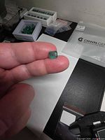 Octagon-cut emerald held between fingers