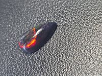 Teardrop black opal showing red flash on dark body
