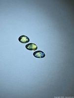 Three oval rose-cut blue-yellow sapphires on neutral background