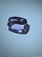 Oblique view of cushion cut amethyst showing pink-purple body color and faceting