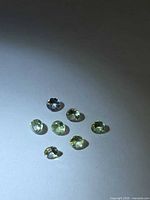 Seven round faceted greenish tanzanite stones on white background