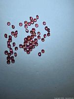 Scatter of small round orange-pink sapphires on light background