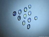 11 oval faceted tanzanites arranged on neutral background