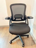 Front view of black mesh office chair showing seat, arms, mesh back