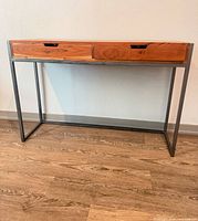 Front view of table showing wood top, two drawers, metal frame