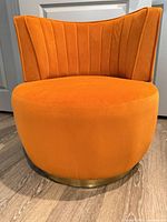 Front view of orange swivel chair showing channel-tufted back and brass base