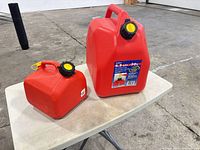 Two red fuel cans 20L and 4L on table