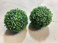 Two artificial boxwood topiary balls on floor
