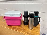 cooler and three thermoses grouped on surface