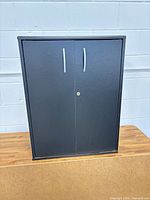 Front view of black cabinet with double doors and silver handles