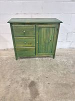 Front view of green stained pine cabinet with drawers and door
