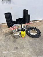 Lot overview showing stacked black pots, trays, bamboo stakes, sprayers, hoses