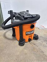 Ridgid 12-gallon shop vacuum with hose attached, accessories visible