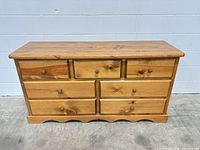 Front view of solid pine dresser showing all seven drawers and scalloped base