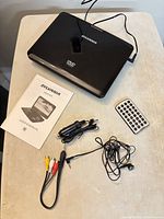 Closed Sylvania DVD player with accessories laid out