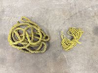 Thick and thin yellow ropes side by side on concrete