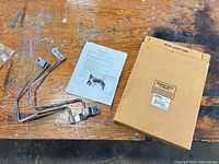 Box, both chrome support brackets, instruction sheet displayed on workbench