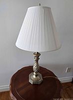 Full view of antiqued gold-tone twist-column lamp with pleated shade