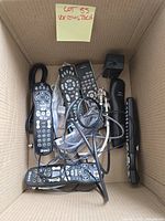 Box containing multiple remotes, coax cables, telephone handset and small electronics