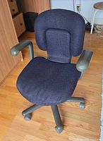 Front view of gray plastic office chair with blue fabric upholstery on wood floor