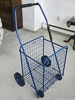 Blue wire shopping cart, side view showing basket, wheels and handle