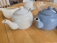 Close of white and blue teapots with spouts and lids visible