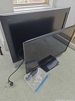 Samsung and Panasonic TVs with cords and remote on floor