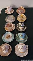 Ten teacup and saucer sets in two columns showing variety of colours and gilt patterns