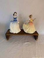 Front view of both figurines on small wooden stand