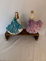 Front view of both Royal Doulton figurines on small wooden stand