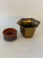 Hexagonal brass planter and terracotta planter in stand side by side