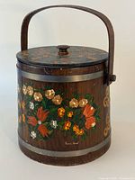 Front view of wooden ice bucket showing floral painting, handle up
