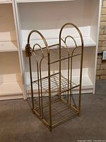 Full view of brass three-shelf unit showing arched sides and wire shelves