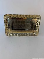 Front view of brass tray displaying embossed design and scalloped rim