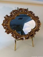 Front view of ornate plaster gilt gold wall mirror on stand