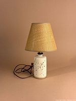 Full view of speckled pottery jug lamp with shade shown for scale