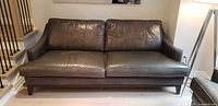 Full front view of brown leather sofa showing overall design and tapered legs