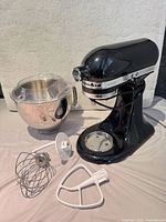 Front angled view of mixer with bowl, pour shield, whisk, dough hook, flat beater