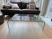 Front view of bent glass coffee table in front of sofa