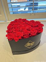 Front view of heart-shaped box showing preserved red roses and gold logo