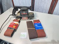 Belt sander with three sanding belt packs on table