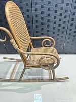 Side view of bentwood child rocking chair showing scroll arms, cane seat and back