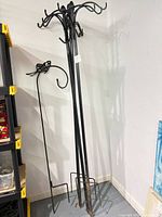 Full view of four wrought iron shepherd hooks leaning against wall