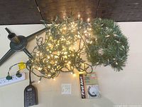Full lot showing light string illuminated, garland, tree stand, mechanical timer package, digital timer