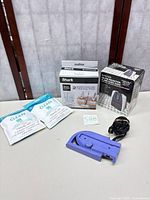 Group shot of all items: travel iron, Craig clock box, Shark mop box, two iFLYsmart travel kits