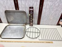 All lot items together: two-piece aluminum pan, round trivet, rectangular rack, boxed cookie press