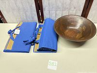 Wooden segmented bowl and two rolled woven grass beach mats with blue fabric trim