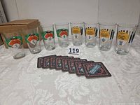 Full lot showing 8 printed pint glasses, 8 coasters, and cardboard box