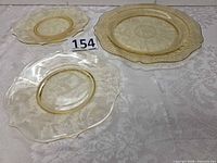 Three depression glass plates laid out showing relative sizes and patterns